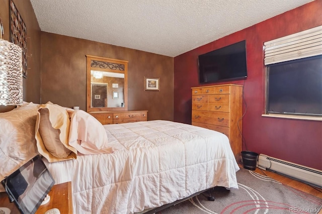 bedroom featuring a textured ceiling, wood finished floors, and a baseboard heating unit