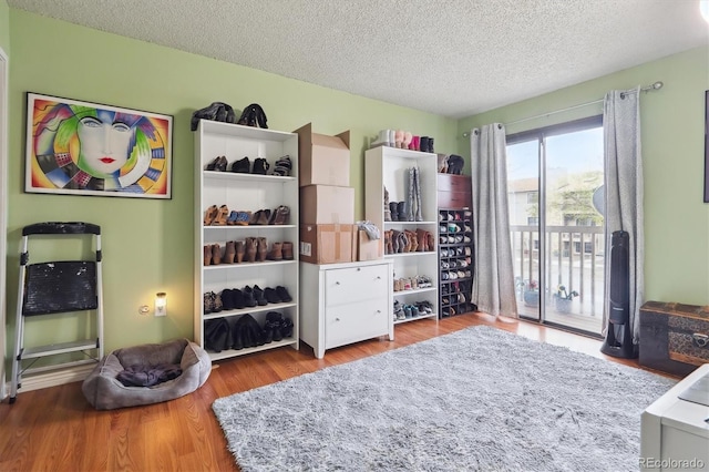 bedroom featuring access to exterior, a textured ceiling, and wood finished floors