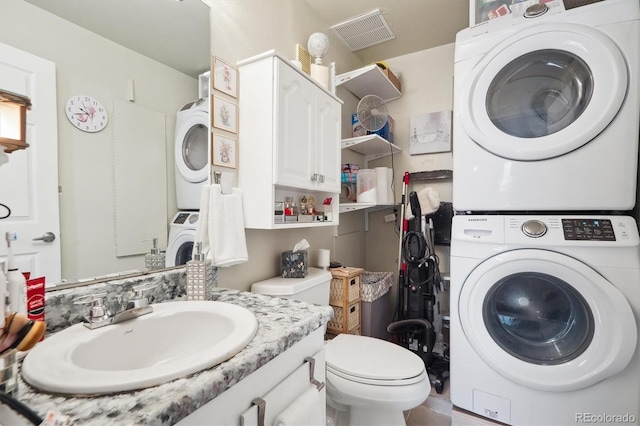 washroom featuring stacked washer and dryer, visible vents, laundry area, and a sink