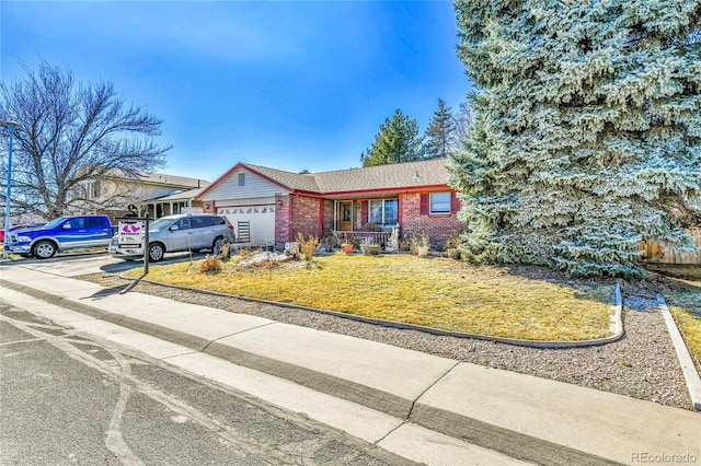 single story home featuring a garage, driveway, brick siding, and a front lawn