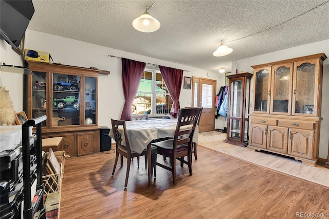 dining space with a textured ceiling and light wood finished floors