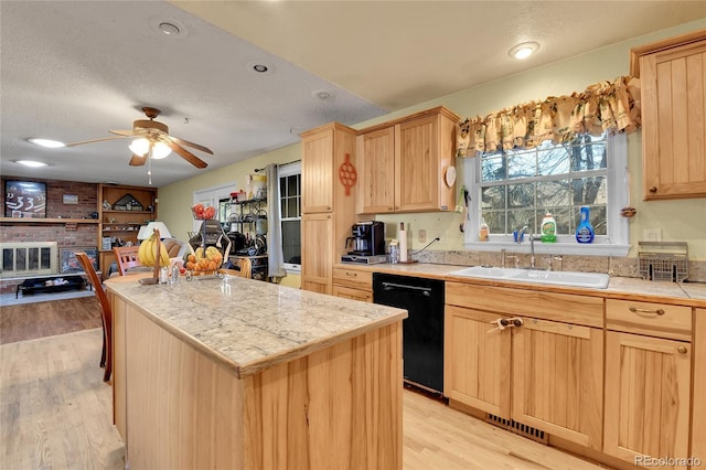 kitchen featuring dishwasher, light brown cabinets, a sink, and a center island