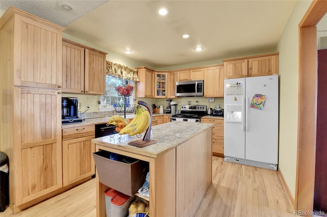 kitchen featuring stainless steel appliances, light brown cabinetry, light wood-type flooring, and light countertops