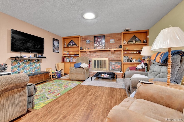 living room featuring built in features, a fireplace, a textured ceiling, and wood finished floors