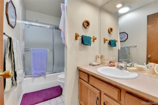 full bath featuring toilet, shower / bath combination with glass door, and vanity