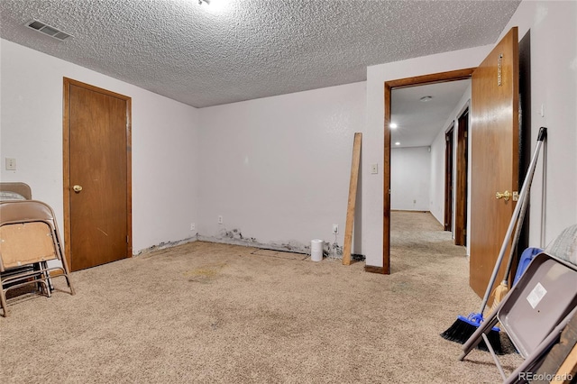 carpeted spare room featuring visible vents and a textured ceiling