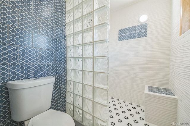 bathroom featuring toilet, tile walls, and tiled shower