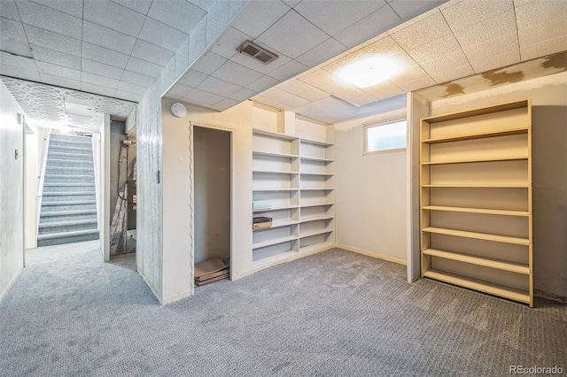 basement with a paneled ceiling and carpet