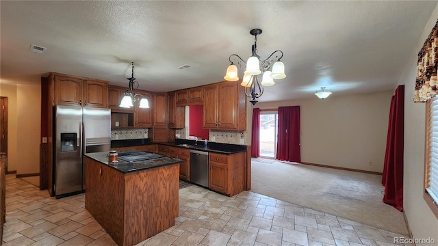 kitchen with pendant lighting, sink, appliances with stainless steel finishes, backsplash, and a kitchen island