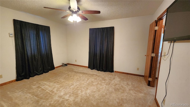 unfurnished room with ceiling fan, light colored carpet, and a textured ceiling