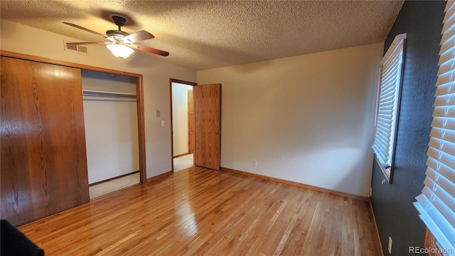 unfurnished bedroom featuring a textured ceiling, light hardwood / wood-style flooring, a closet, and ceiling fan