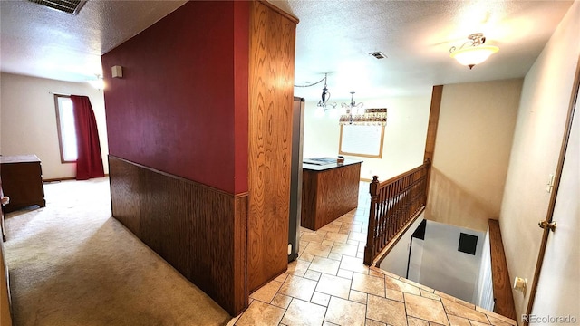 corridor with light carpet and a textured ceiling