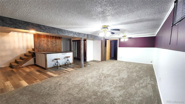 basement featuring bar, hardwood / wood-style floors, and ceiling fan