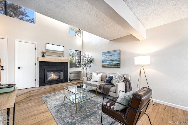 living room with hardwood / wood-style floors, a towering ceiling, and a textured ceiling