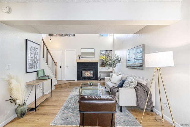 living room with a tiled fireplace and light wood-type flooring