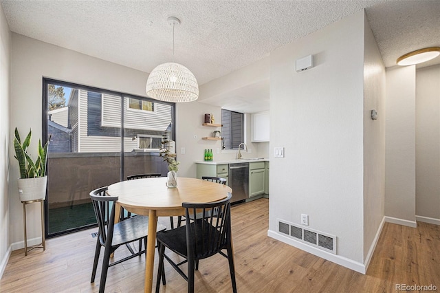 dining space with sink, a textured ceiling, and light hardwood / wood-style flooring