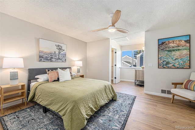 bedroom with a textured ceiling, light hardwood / wood-style flooring, and ceiling fan