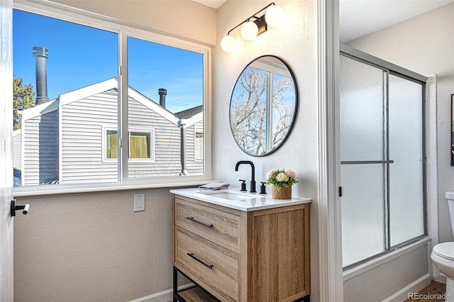 full bathroom featuring vanity, combined bath / shower with glass door, and toilet