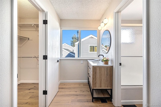 bathroom with wood-type flooring, vanity, and a textured ceiling