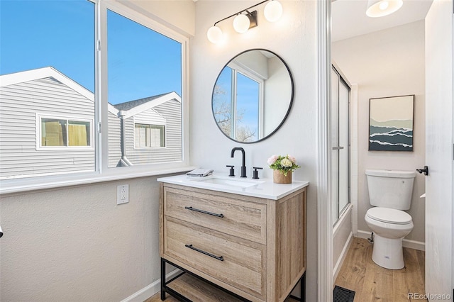 full bathroom featuring hardwood / wood-style flooring, vanity, toilet, and shower / bath combination with glass door