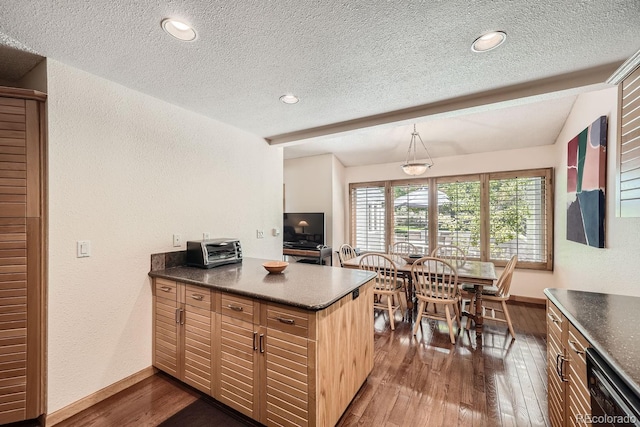 kitchen featuring a peninsula, a textured ceiling, a textured wall, and dark wood-type flooring