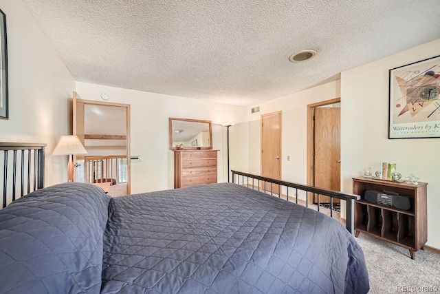 bedroom featuring a textured ceiling, visible vents, and carpet
