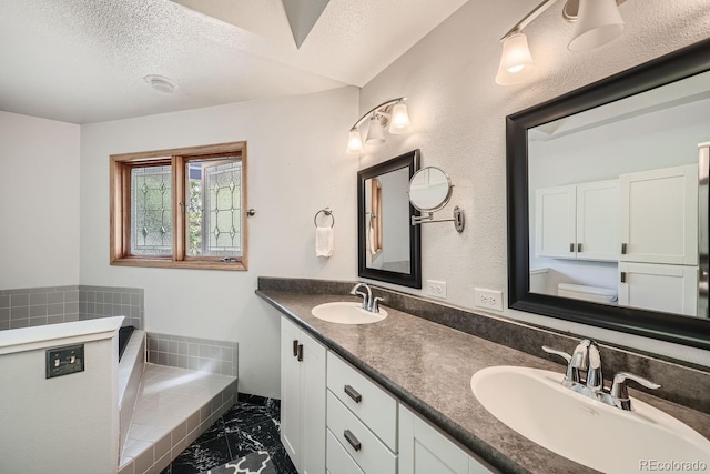 full bath with double vanity, a textured ceiling, a sink, and marble finish floor
