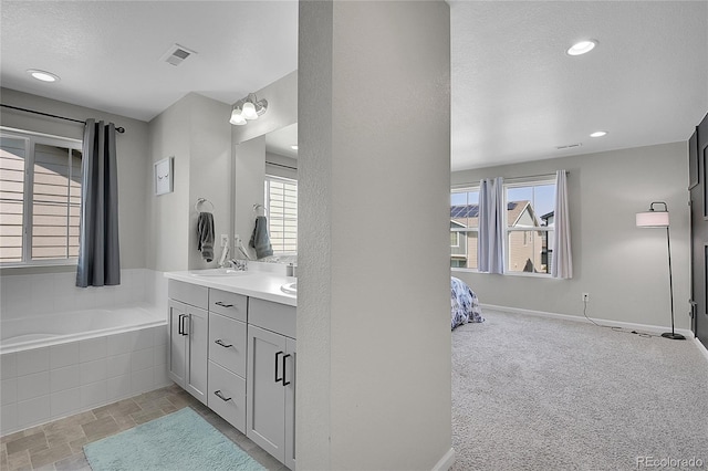 bathroom featuring a relaxing tiled tub, a textured ceiling, and vanity