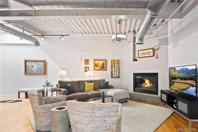 living area with wood finished floors, a glass covered fireplace, and baseboards