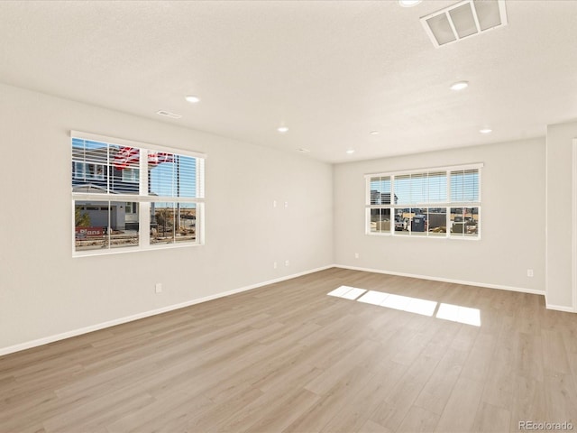 unfurnished room featuring light hardwood / wood-style floors, a textured ceiling, and a wealth of natural light