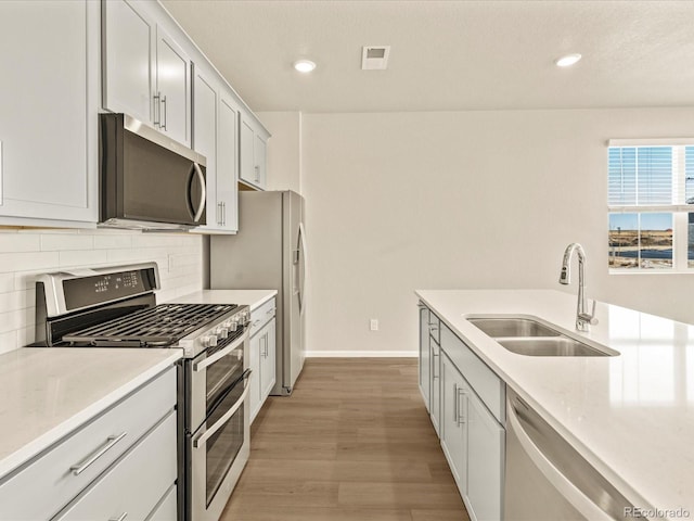 kitchen with stainless steel appliances, tasteful backsplash, sink, and white cabinets