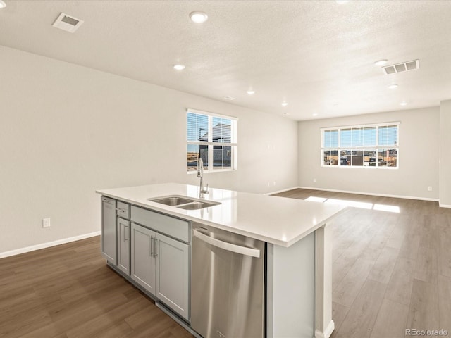 kitchen featuring hardwood / wood-style floors, dishwasher, an island with sink, sink, and gray cabinetry