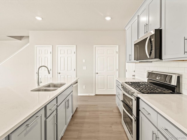 kitchen with stainless steel appliances, tasteful backsplash, sink, and light hardwood / wood-style floors