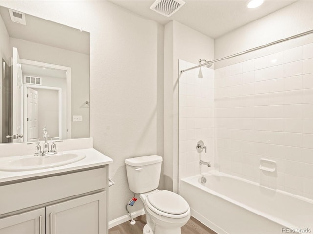 full bathroom featuring wood-type flooring, toilet, tiled shower / bath combo, and vanity