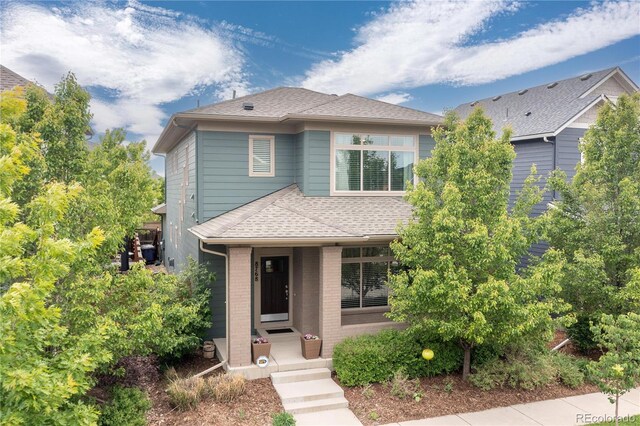 8768 E 54th Pl, Denver, CO 80238 - view of front of property featuring a shingled roof, brick siding, and a porch