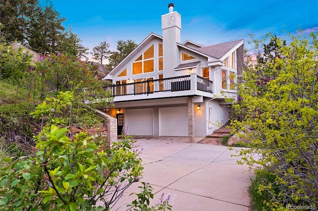 9001 Eastridge Rd, Golden, CO 80403 - view of front of home featuring a chimney, a balcony, stucco siding, concrete driveway, and a garage