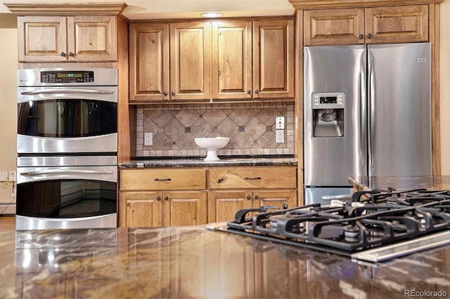 9001 Eastridge Rd, Golden, CO 80403 - kitchen with appliances with stainless steel finishes, decorative backsplash, dark stone counters, and brown cabinetry
