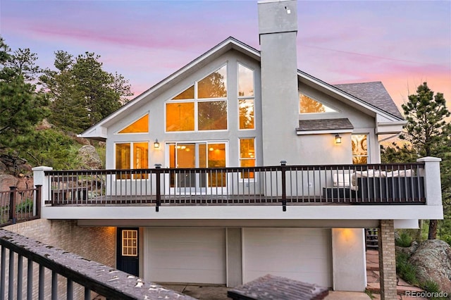 9001 Eastridge Rd, Golden, CO 80403 - back of property at dusk featuring a chimney, an attached garage, stucco siding, and a shingled roof