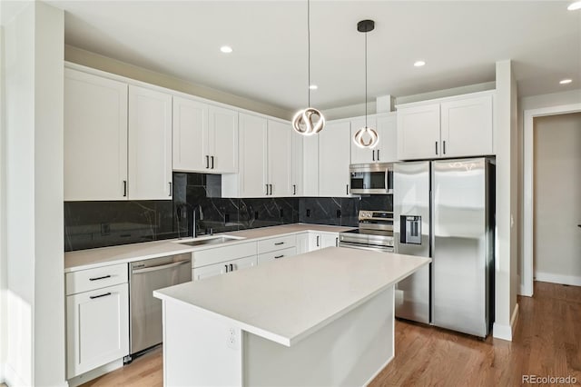1559 N Hooker St, Denver, CO 80204 - kitchen with stainless steel appliances, light wood finished floors, white cabinetry, a kitchen island, and backsplash