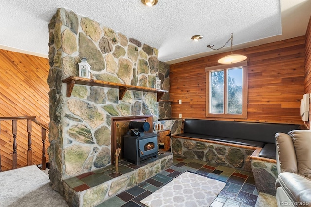 living room with a wood stove, a textured ceiling, and wooden walls