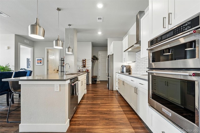 20 Wilcox St Unit 208, Castle Rock, CO 80104 - kitchen featuring appliances with stainless steel finishes, dark wood finished floors, wall chimney exhaust hood, a breakfast bar area, and an island with sink