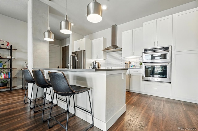 20 Wilcox St Unit 208, Castle Rock, CO 80104 - kitchen with wall chimney exhaust hood, stainless steel appliances, a breakfast bar, and dark wood finished floors