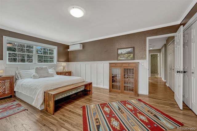 bedroom with an AC wall unit, crown molding, and light hardwood / wood-style flooring