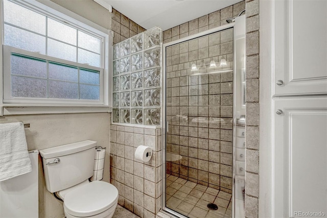 bathroom featuring tiled shower and toilet