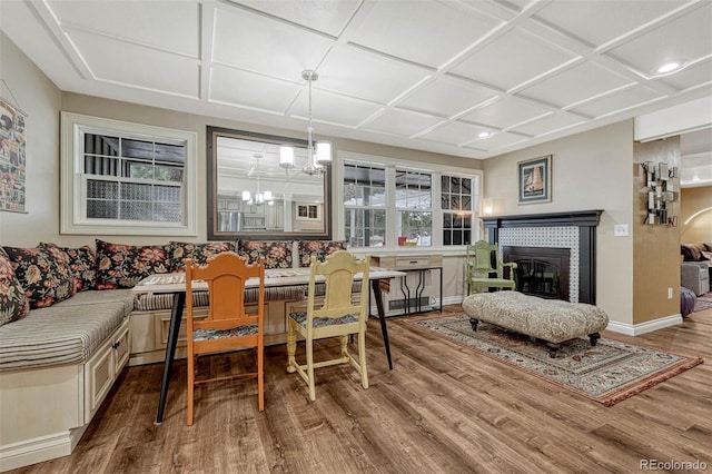 dining space with a tile fireplace, an inviting chandelier, coffered ceiling, breakfast area, and wood-type flooring