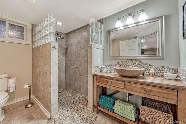 bathroom featuring tiled shower, vanity, and toilet