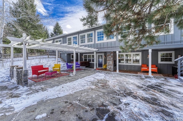 snow covered back of property featuring a pergola