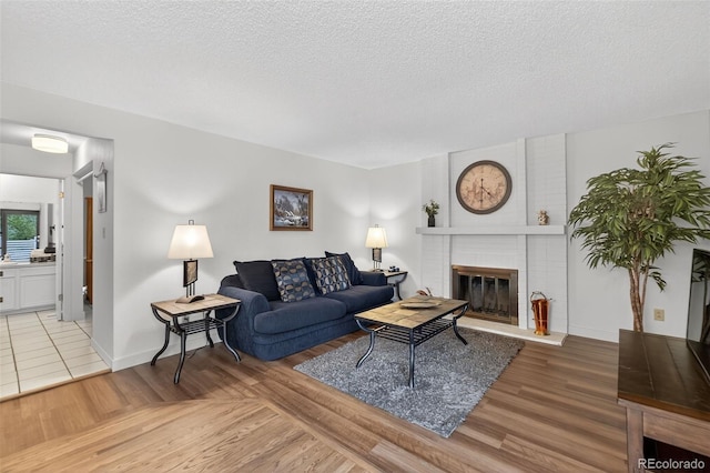 3070 W Enchanted Cir, Colorado Springs, CO 80917 - living room featuring a fireplace, light wood-style floors, a textured ceiling, and baseboards