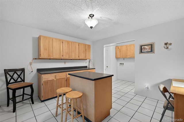 3070 W Enchanted Cir, Colorado Springs, CO 80917 - kitchen with dark countertops, a kitchen island, light tile patterned floors, a textured ceiling, and baseboards