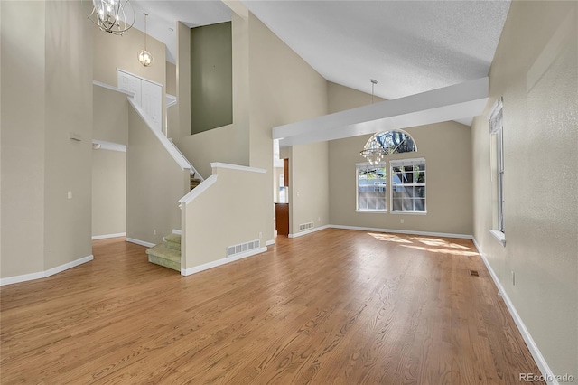 9008 W 101st Ave, Broomfield, CO 80021 - unfurnished living room with a chandelier, wood finished floors, stairway, and high vaulted ceiling